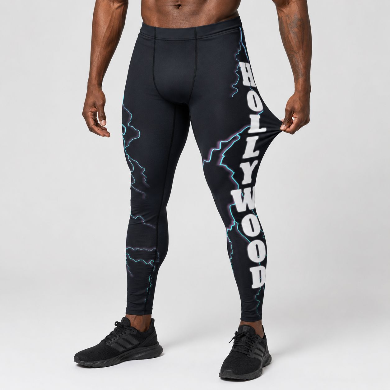 Person wearing black leggings with 'Hollywood' text and lightning designs on a white background