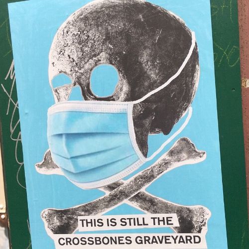 Skull and crossbones wearing a face mask - sign at Crossbones burial site in Southwark