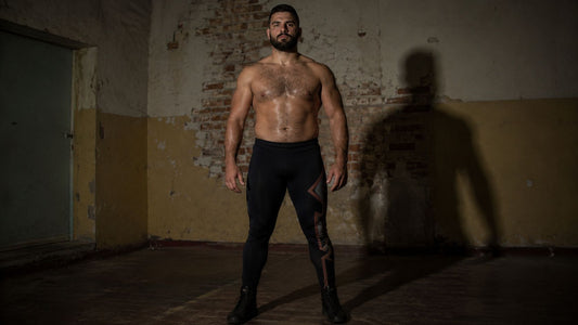 Tall stocky wrestler standing in darkened room in France