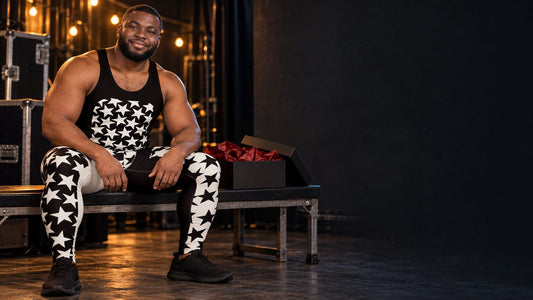 Man in black and white star print wrestling tights and matching tank top sitting backstage beside an open gift box