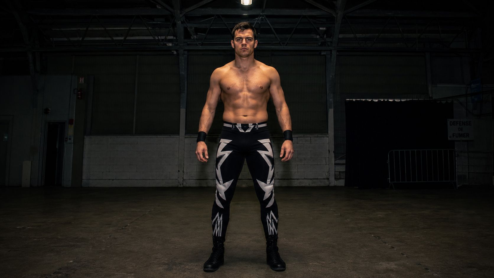 man in bold full-length pro wrestling tights, raw confrontational energy, industrial venue