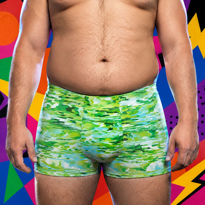 Person wearing green camouflage boxer briefs against a colorful abstract background