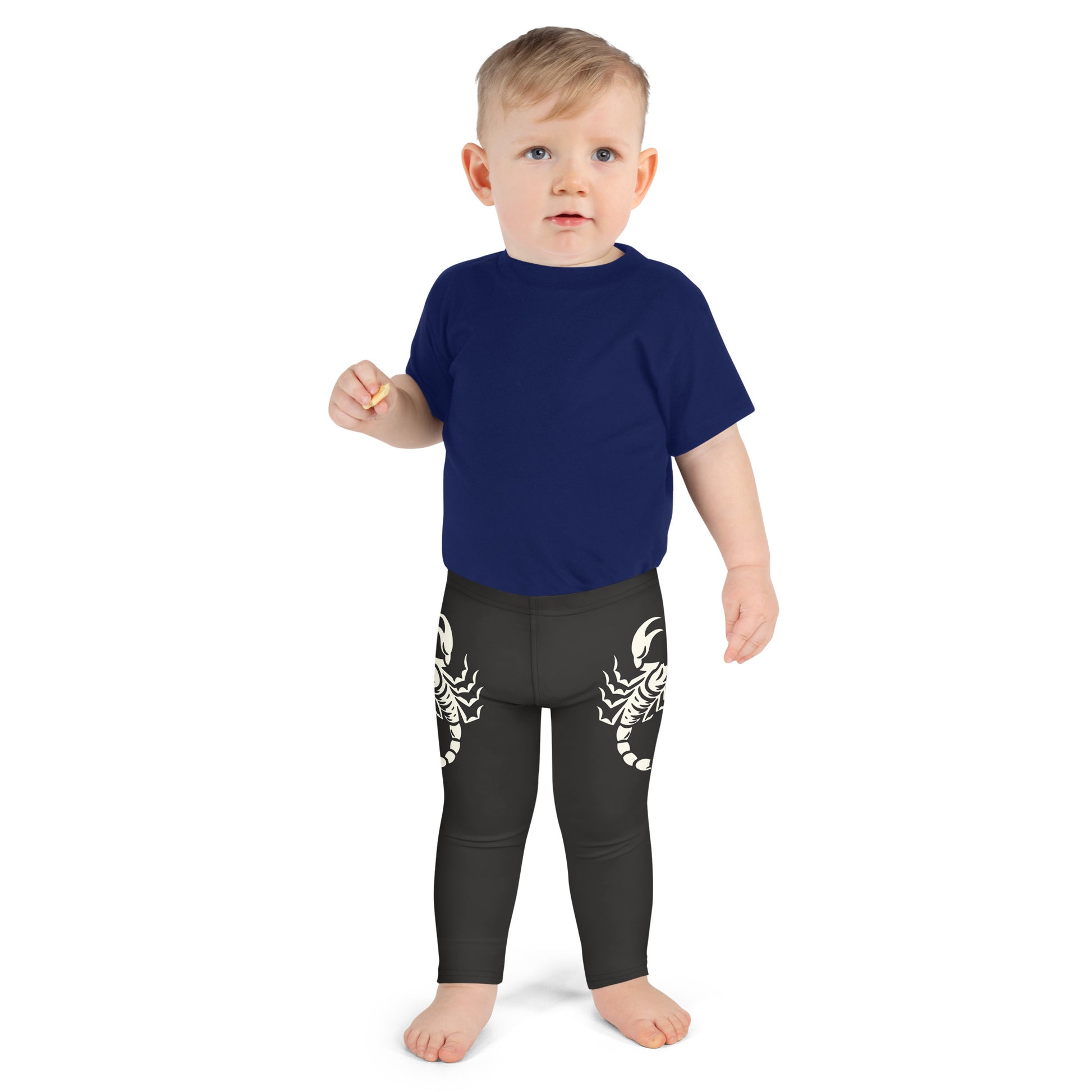Toddler wearing dark leggings with large printed scorpion on each side, laid flat