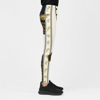 A side-profile view of a youth wearing high-waisted, black athletic leggings with a prominent gold and black ornate pattern down the center and sides, paired with black sneakers against a plain white studio background.