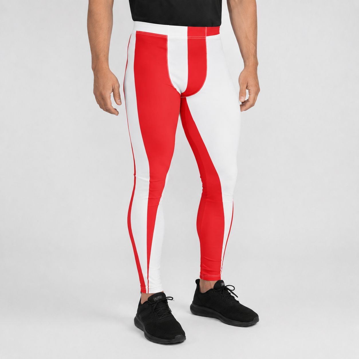 A person wearing color-blocked athletic leggings with bold red and white striped panels, paired with black sneakers, shown from the waist down on a light gray studio background.