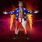 A shirtless male wrestler stands with arms outstretched in a smoky arena, wearing a blue open jacket with white stars, red-and-white striped pants, and black boots. Flames rise behind him, and the background is lit in red and magenta tones.