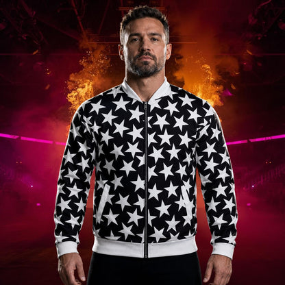 A man wearing a black and white star-patterned zip-up bomber jacket, standing against a dramatic red and orange background with smoke and stage lighting.