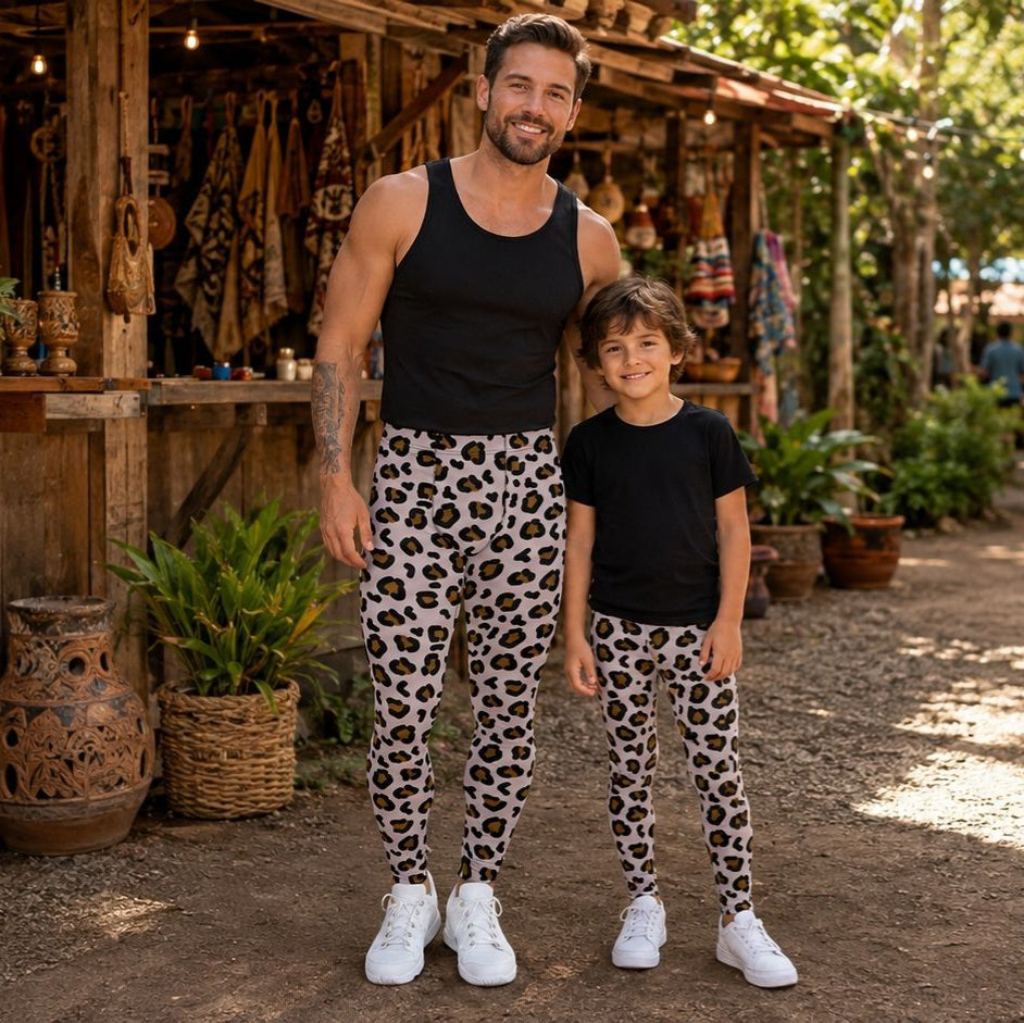 A man and a child standing outdoors in front of a rustic wooden shop, wearing matching black tank top and t-shirt tops with matching leopard-print leggings.