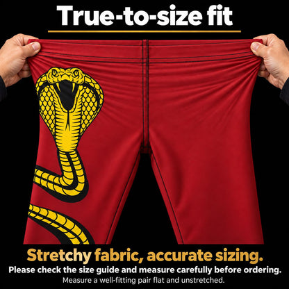 Red athletic shorts with a large yellow and black cobra snake graphic on the left leg, being stretched by two hands against a black background. Text at the top reads 'True-to-size fit' and text at the bottom describes stretchy fabric and accurate sizing.