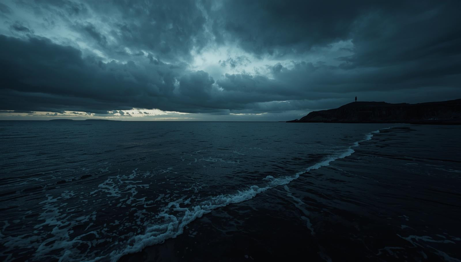 Gruselige, dramatische, gotische Küste. Einsame Gestalt auf Landzunge sichtbar. Düsterer, bewölkter Himmel.