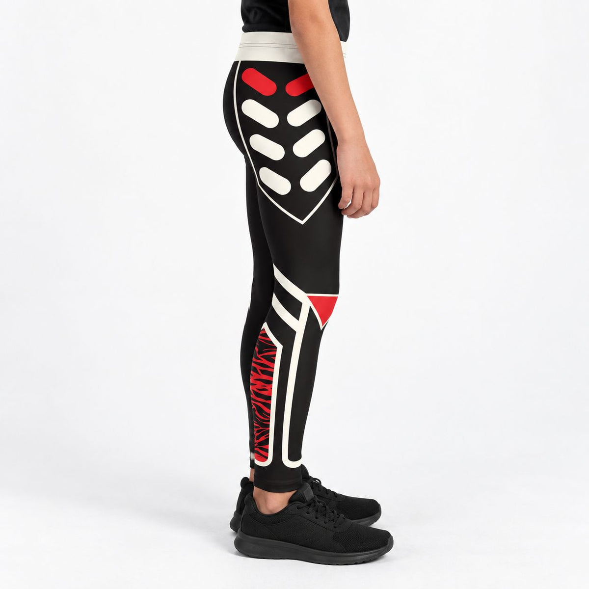 A person wearing black leggings with a bold white and red geometric graphic print, shown from the waist down against a clean white studio background.