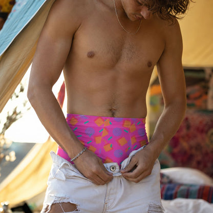 Man wearing pink 80s Memphis style geometric patterned boxer briefs in relaxed setting, pulling up ripped white jeans over the top.