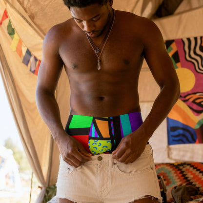 Man wearing colorful 80s Memphis style boxer briefs inside a tent with a vibrant interior.