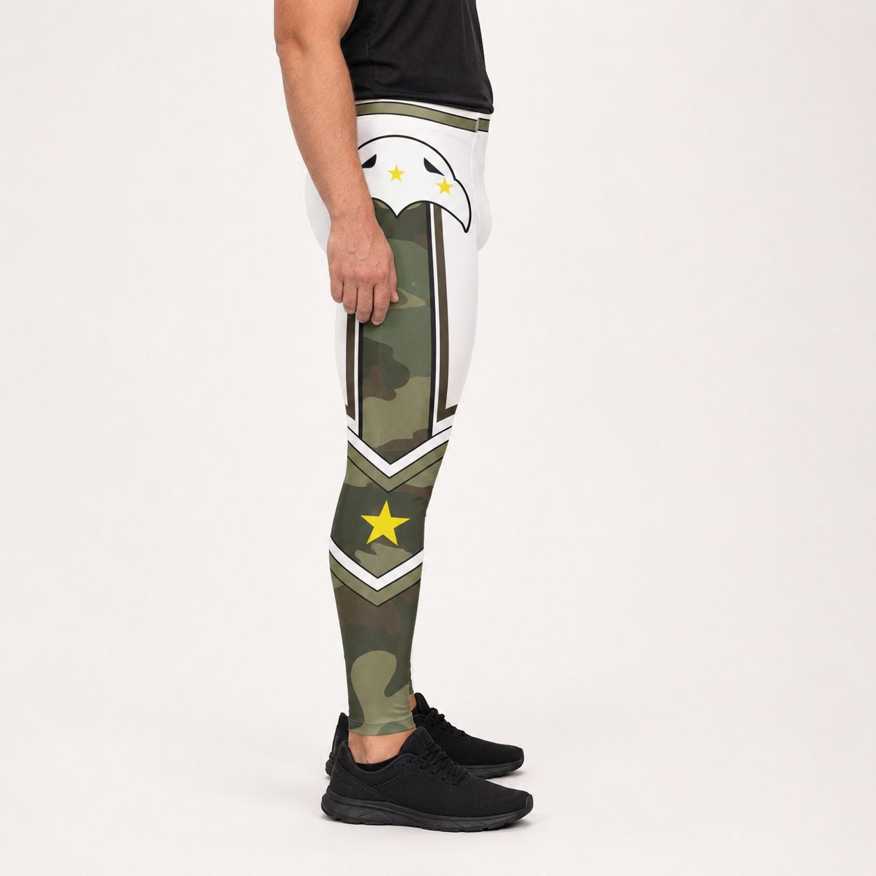 A side view of a person wearing camouflage print leggings with military-style insignia patches, a black t-shirt, and black sneakers, set against a plain white studio background.
