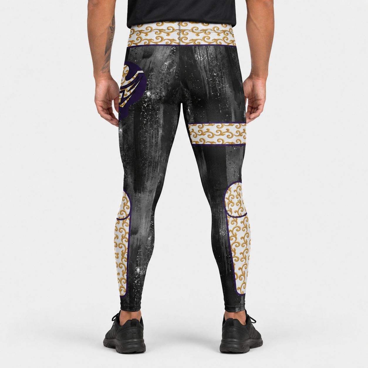 Black printed leggings with printed gold brocade and white patterns worn by a person on a white background