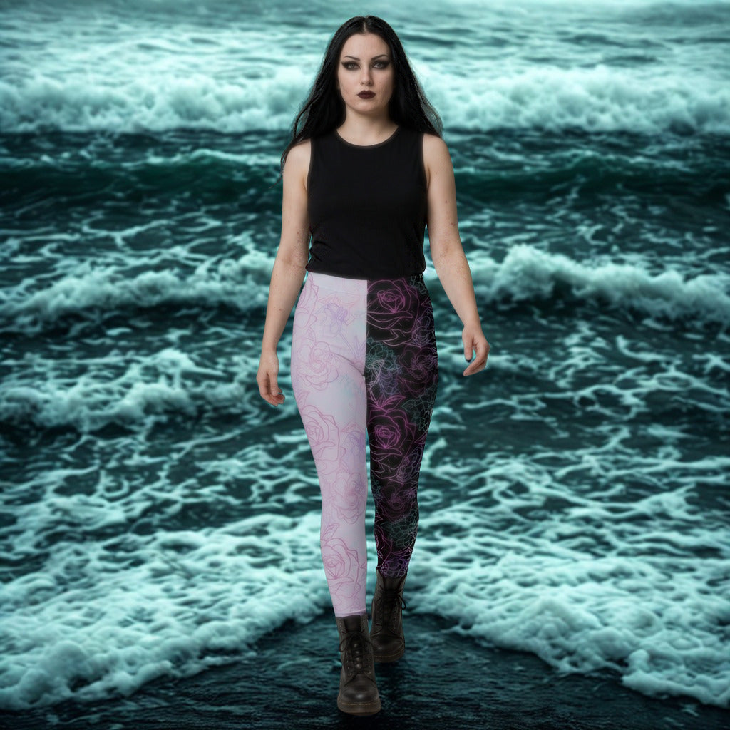 Woman wearing a black top and patterned pastel goth leggings standing in front of gothic ocean waves