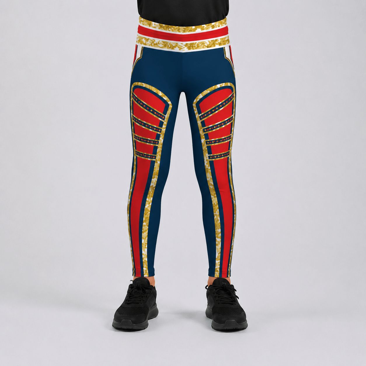 A person wearing navy blue leggings with red and gold military-style panel designs, paired with black sneakers, shown from the waist down against a light gray studio background.