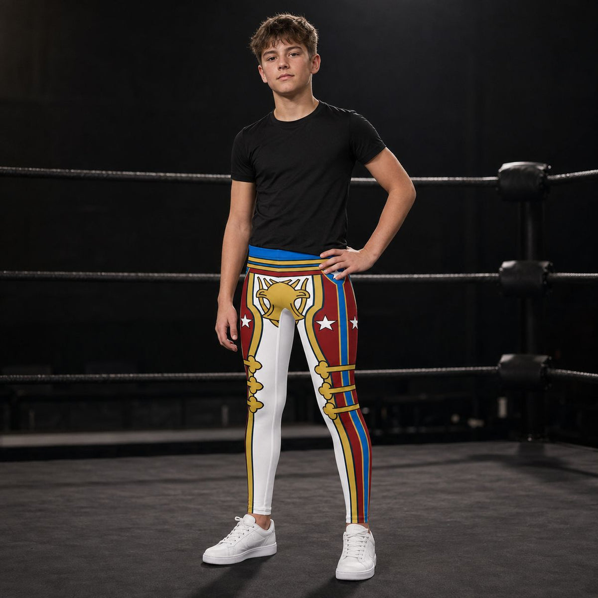 A young man stands in a boxing ring wearing colorful, graphic-printed cosplay wrestling tights with a white, red, blue, and gold retro military American hero design, a black t-shirt, and white sneakers.