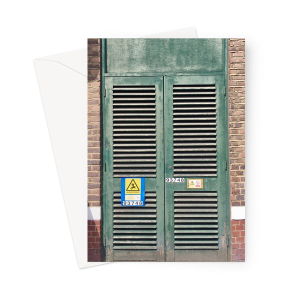 Greeting card showing a faded-green electricity cupboard set in a brick wall. A yellow and blue safety warning is attached to the left side, with a serial number.