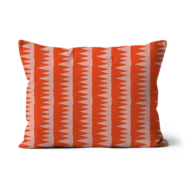 This Mid-Century Modern style couch pillow design consists of colorful pink jagged columns of geometric triangular shapes stacked upon each other like columns against an orange red background