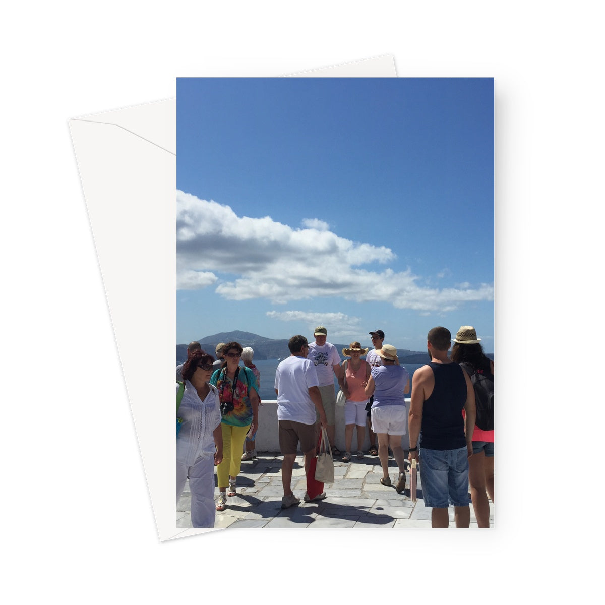 Tourists obscuring the view of the caledera off the coast of Santorni. Large sky in the top half of this greeting card