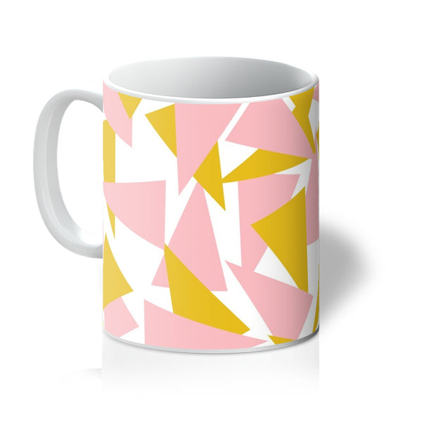 This Mid-Century Modern style ceramic mug consists of colorful triangle shapes in pink and orange on a white background
