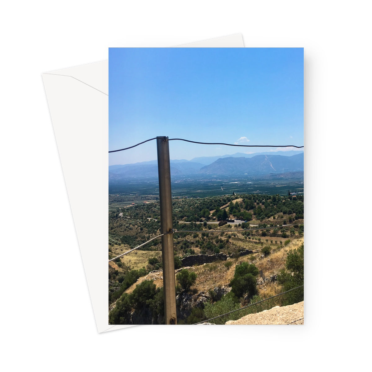 This greeting card shows the view from the top of the ancient Greek settlement in Mycenae, overlooking the Greek countryside. In the foreground is a metal wire fence.