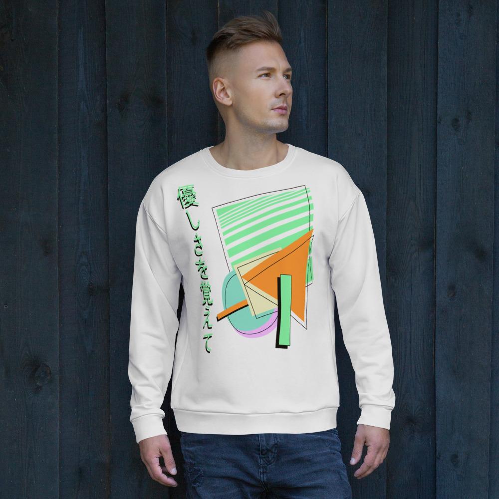 Retro style 90s Vaporwave and 80s Memphis fusion in this sweatshirt design by BillingtonPix, featuring geometric shapes in tones of orange, green, blue and mauve with black line shadow overlays. Japanese phrase 優しさを覚えて is written vertically down the left hand side all against a pale grey background to provide a sharp streetwear visual.