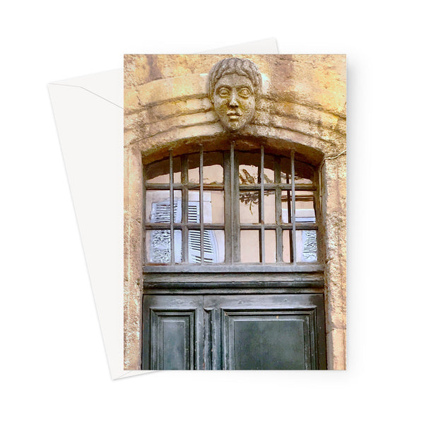 Greeting card showing carved stone head centred above the top half of a doorway, which is painted a dark green-black colour