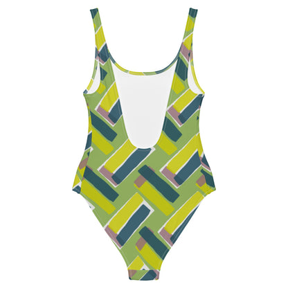 This cheeky, stylish and comfortable, abstract design patterned swimsuit is entitled Forever Connected and consists of diagonal color blocks of olive green, mustard yellow and pink putty in an alternating criss-cross format on a green background