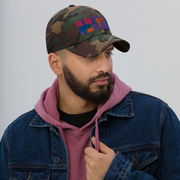 Colorful pink, orange, purple and blue geometric shapes patterned rectangular logo on this green camo colored dad hat