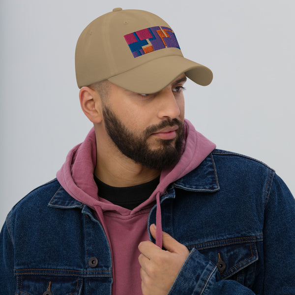 Colorful pink, orange, purple and blue geometric shapes patterned rectangular logo on this khaki colored dad hat