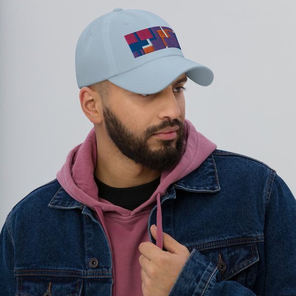 Colorful pink, orange, purple and blue geometric shapes patterned rectangular logo on this light blue colored dad hat