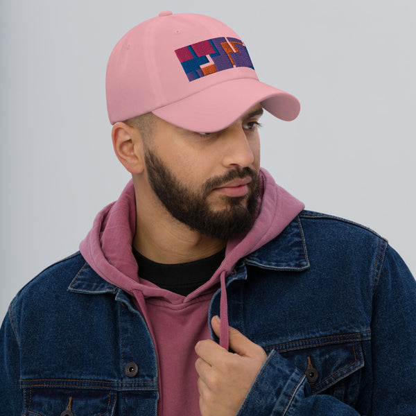 Colorful pink, orange, purple and blue geometric shapes patterned rectangular logo on this pink colored dad hat