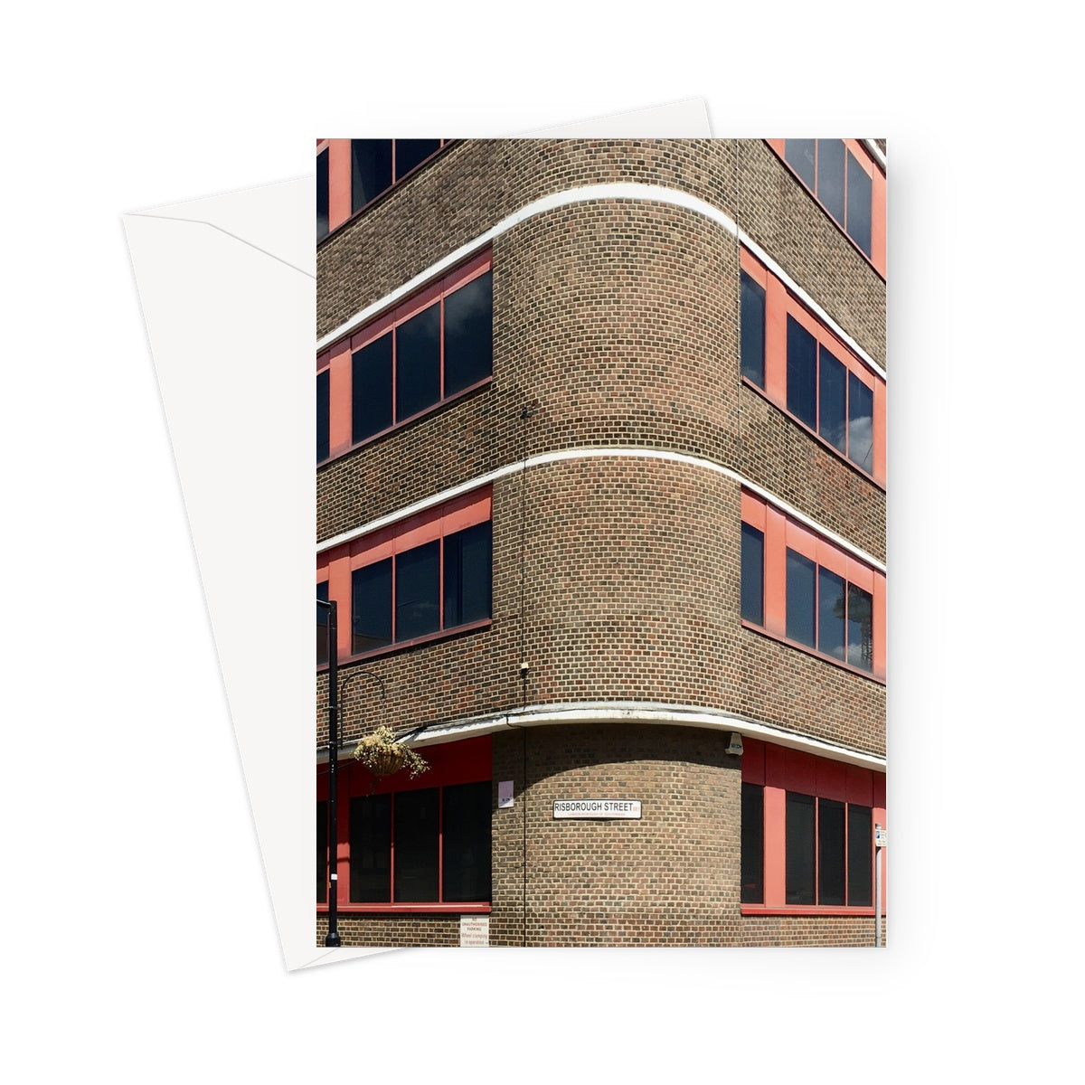 Greeting card showing corner aspect of an Art Deco brick building in Southwark. There is some detail of white stripes and the windows are framed in red metal. A sign at the bottom of the image says "Risborough Street"