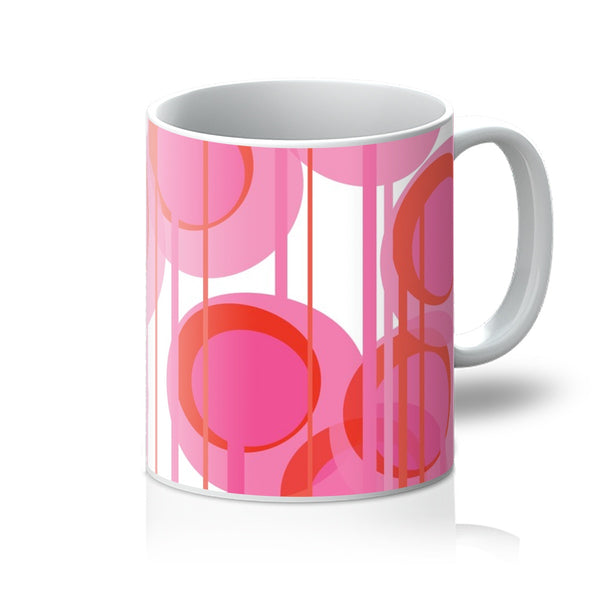 This Mid-Century Modern style coffee or tea mug consists of colorful geometric circular shapes in various tones of pink, connected vertically by narrow tentacles to form and almost hanging mobile type abstract circular pattern on a white background