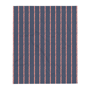 This retro style couch throw consists of jagged vertical seafoam salmon pink stripes against a navy blue background