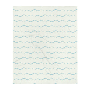 This retro style couch throw consists of a series of horizontal sea-foam blue wave shapes against a pale cream background