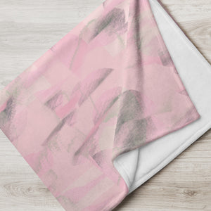 Throw blanket with a subtle pink colored abstract repeat pattern with hints of green and an abstract patterned background