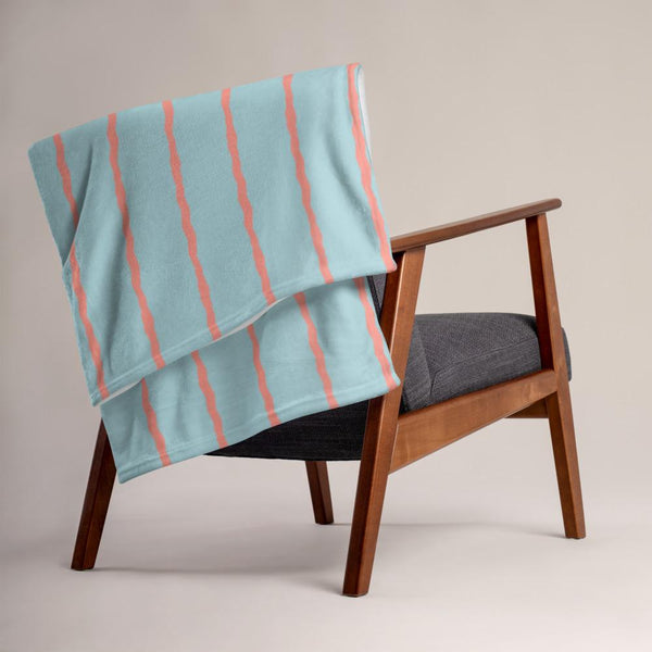 This retro style couch throw consists of jagged vertical seafoam salmon pink stripes against a seafoam blue background