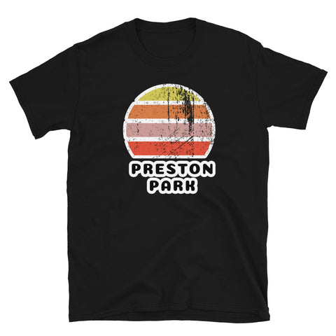 Features a distressed abstract retro sunset graphic in yellow, orange, pink and scarlet stripes rising up from the famous Brighton place name of Preston Park on this black t-shirt