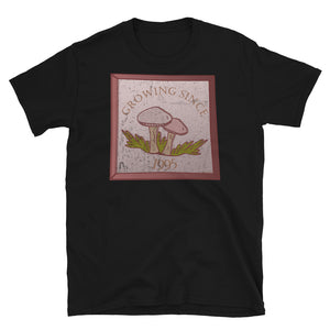 Growing since 1995 cute Goblincore style design with two mushrooms in muted tones and a glass framed effect with distressed look on this black cotton t-shirt by BillingtonPix