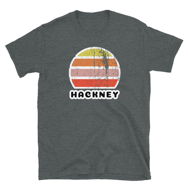 Vintage retro sunset in yellow, orange, pink and scarlet with the name Hackney beneath on this dark heather t-shirt