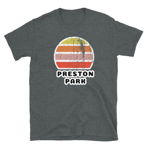 Features a distressed abstract retro sunset graphic in yellow, orange, pink and scarlet stripes rising up from the famous Brighton place name of Preston Park on this dark heather t-shirt