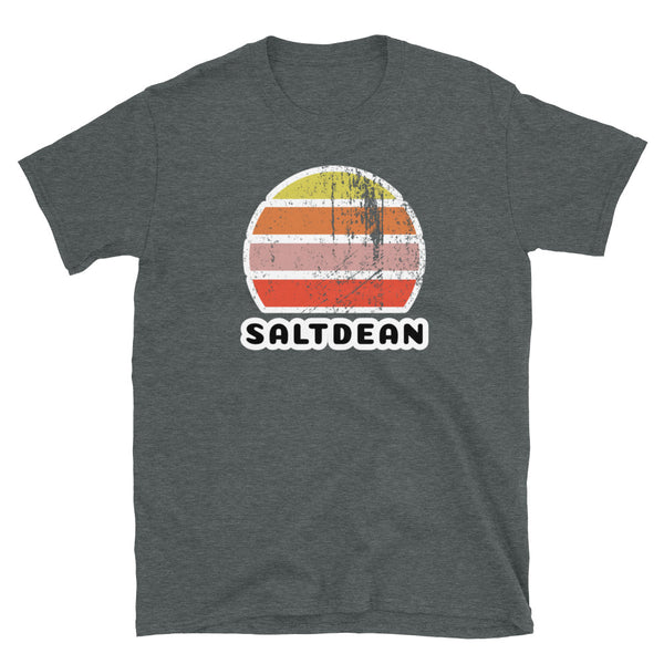 Features a distressed abstract retro sunset graphic in yellow, orange, pink and scarlet stripes rising up from the famous Brighton place name of Saltdean on this dark heather t-shirt