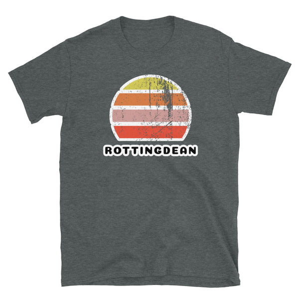 Distressed style abstract retro sunset graphic in yellow, orange, pink and scarlet stripes rising up from the famous Brighton place name of Rottingdean on this dark heather  t-shirt