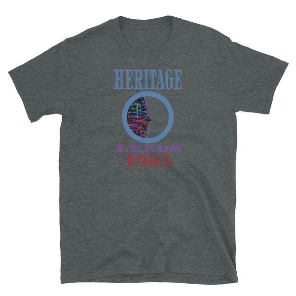Graphic t-shirt with a patterned profile face in abstract design, tones of blue, green, purple, red, in circular format, with the words Heritage Leeds 1983 in blue, purple and red on this dark heather cotton t-shirt by BillingtonPix
