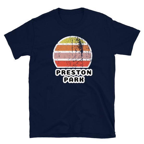 Features a distressed abstract retro sunset graphic in yellow, orange, pink and scarlet stripes rising up from the famous Brighton place name of Preston Park on this navy t-shirt