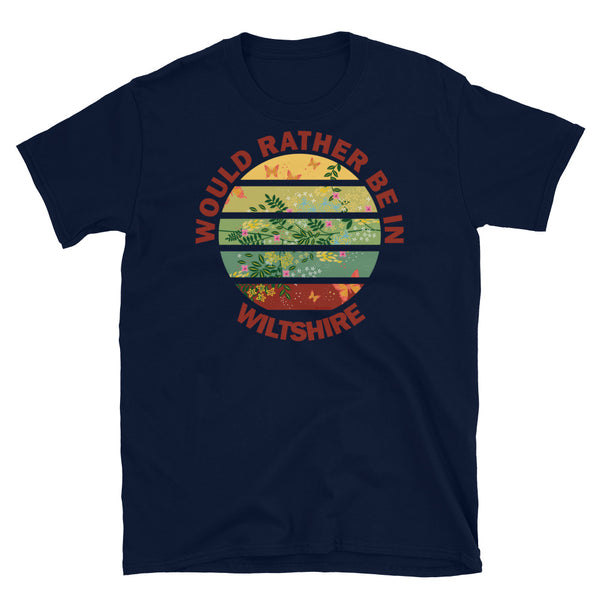 Cottagecore style floral and butterfly design within a Vintage Sunset abstract shape in tones of crimson, teal, green, mustard and yellow stripes with the slogan Would Rather Be in Wiltshire on this navy cotton t-shirt by BillingtonPix