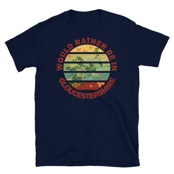 Cottagecore style floral and butterfly design within a Vintage Sunset abstract shape in tones of crimson, teal, green, mustard and yellow stripes with the slogan Would Rather Be in Gloucestershire on this navy cotton t-shirt by BillingtonPix